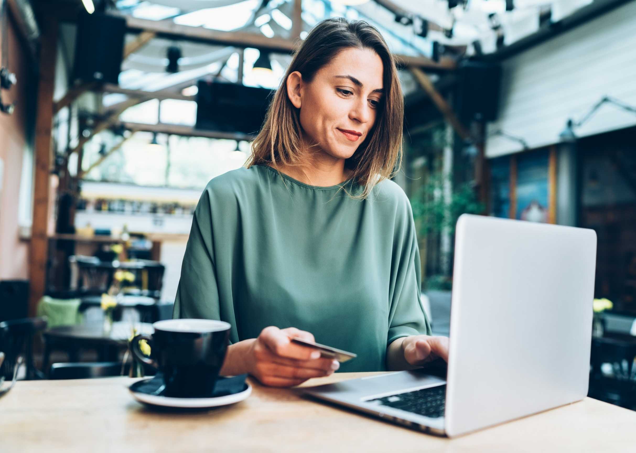 woman-shopping-online-on-her-computer-sitting-at-the-table-in-caffe